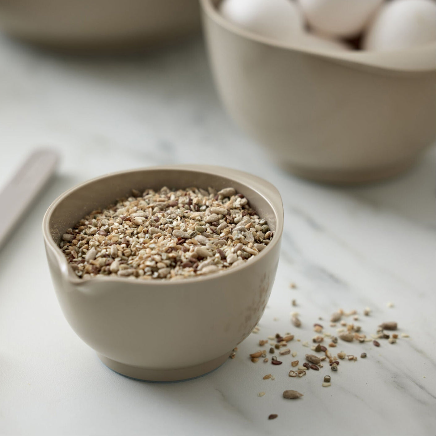 Small beige bowl filled with seeds on a light surface