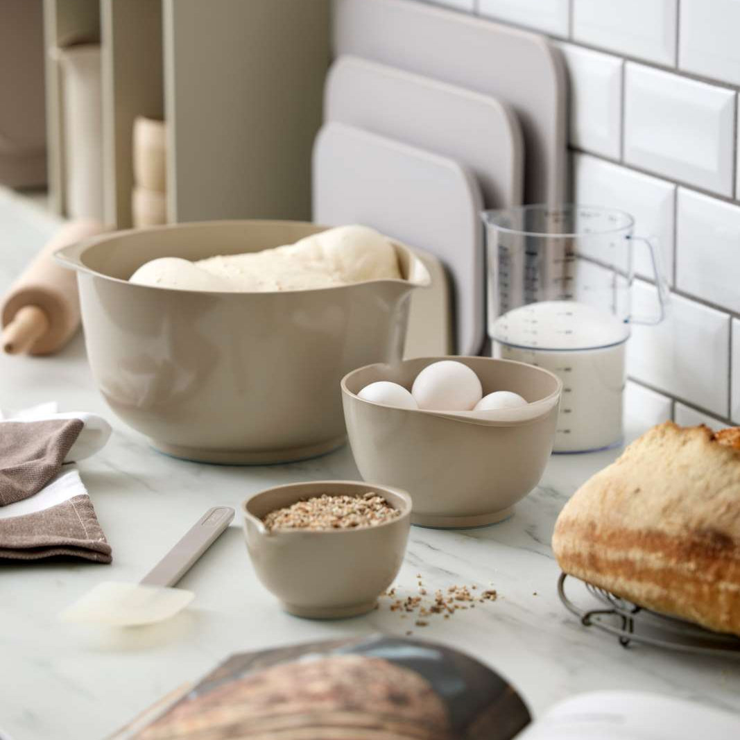 Kitchen counter with bowls, bread, and eggs on a tiled wall background
